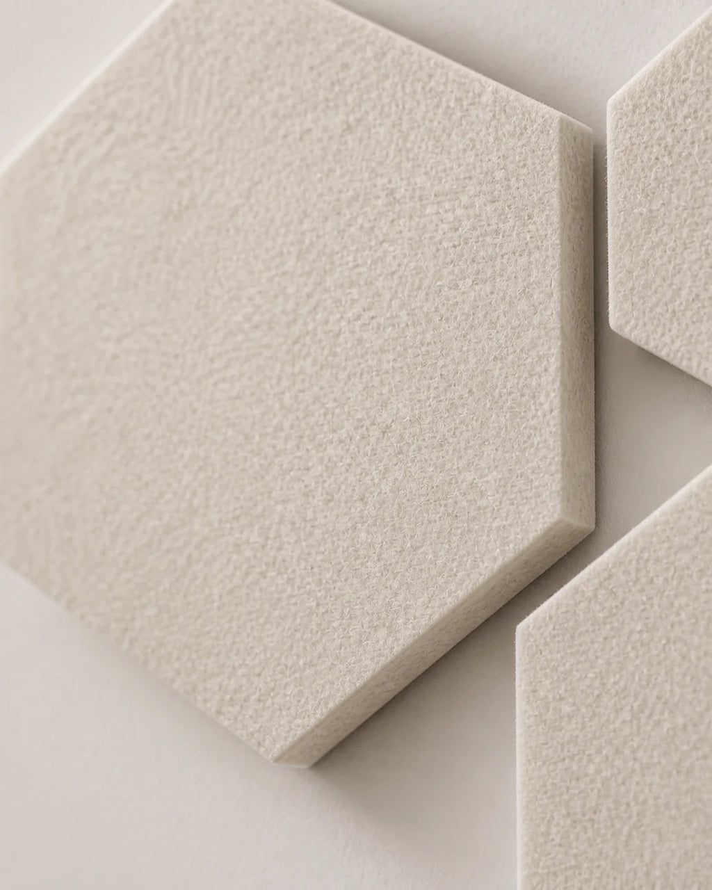Gros plan sur la texture en feutre PET écru du panneau acoustique hexagonal