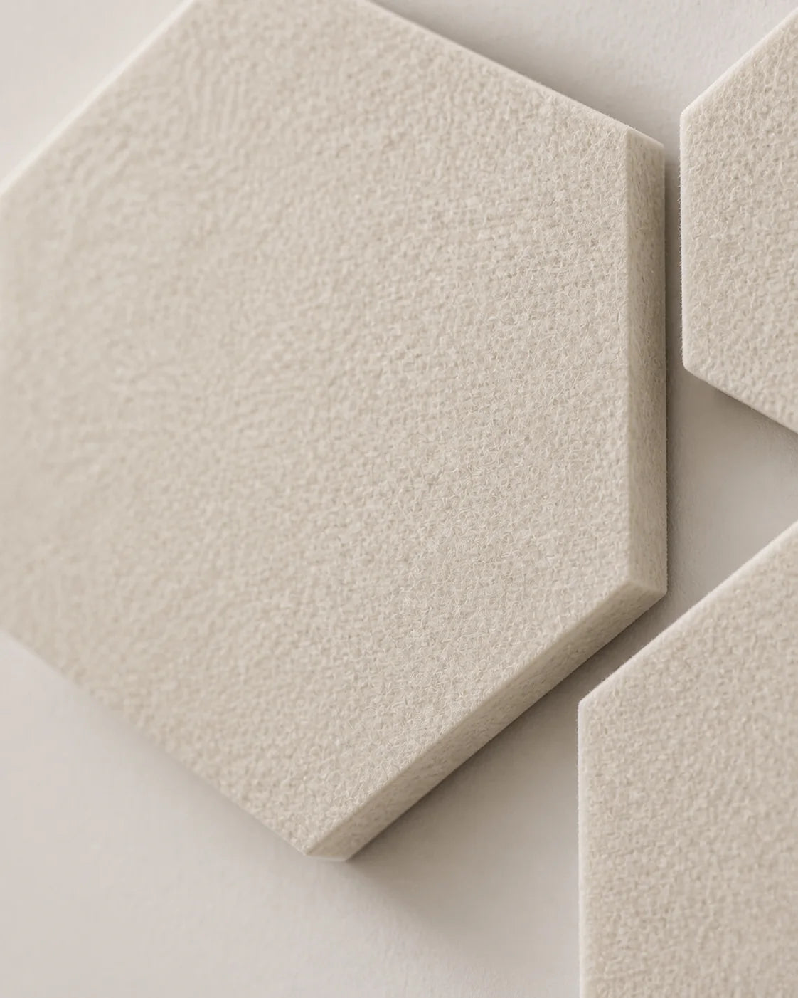 Gros plan sur la texture en feutre PET écru du panneau acoustique hexagonal